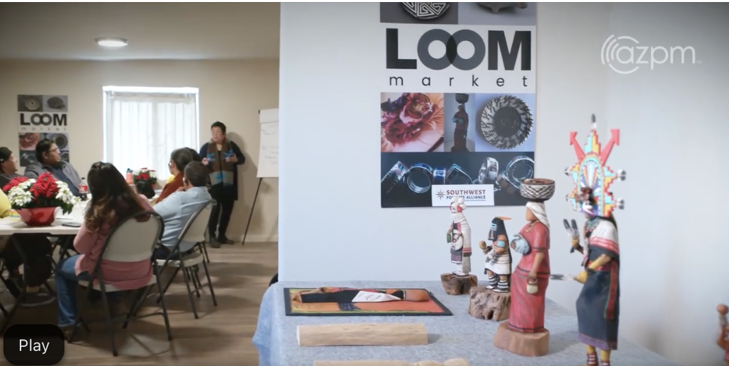 Screenshot of a Loom.Market meeting with carved wooden figures and a Loom poster in the foreground.