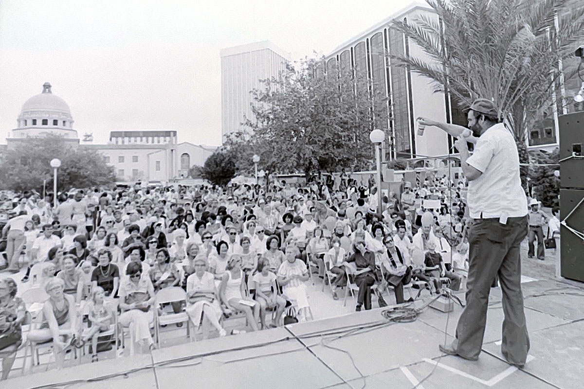 Big Jim, the founder of Tucson Meet Yourself, speaking on a stage at TMY to a crowd of people in 1974.